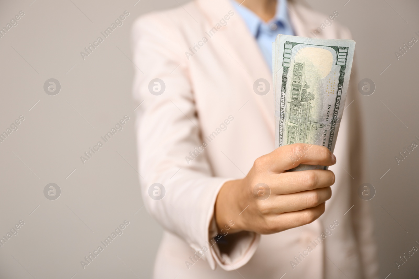 Photo of Young woman holding dollar bills on light grey background, closeup