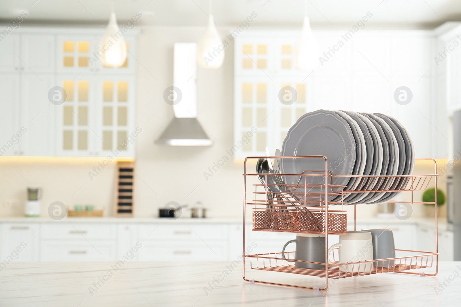 Photo of Drying rack with clean dishes on table in kitchen. Space for text