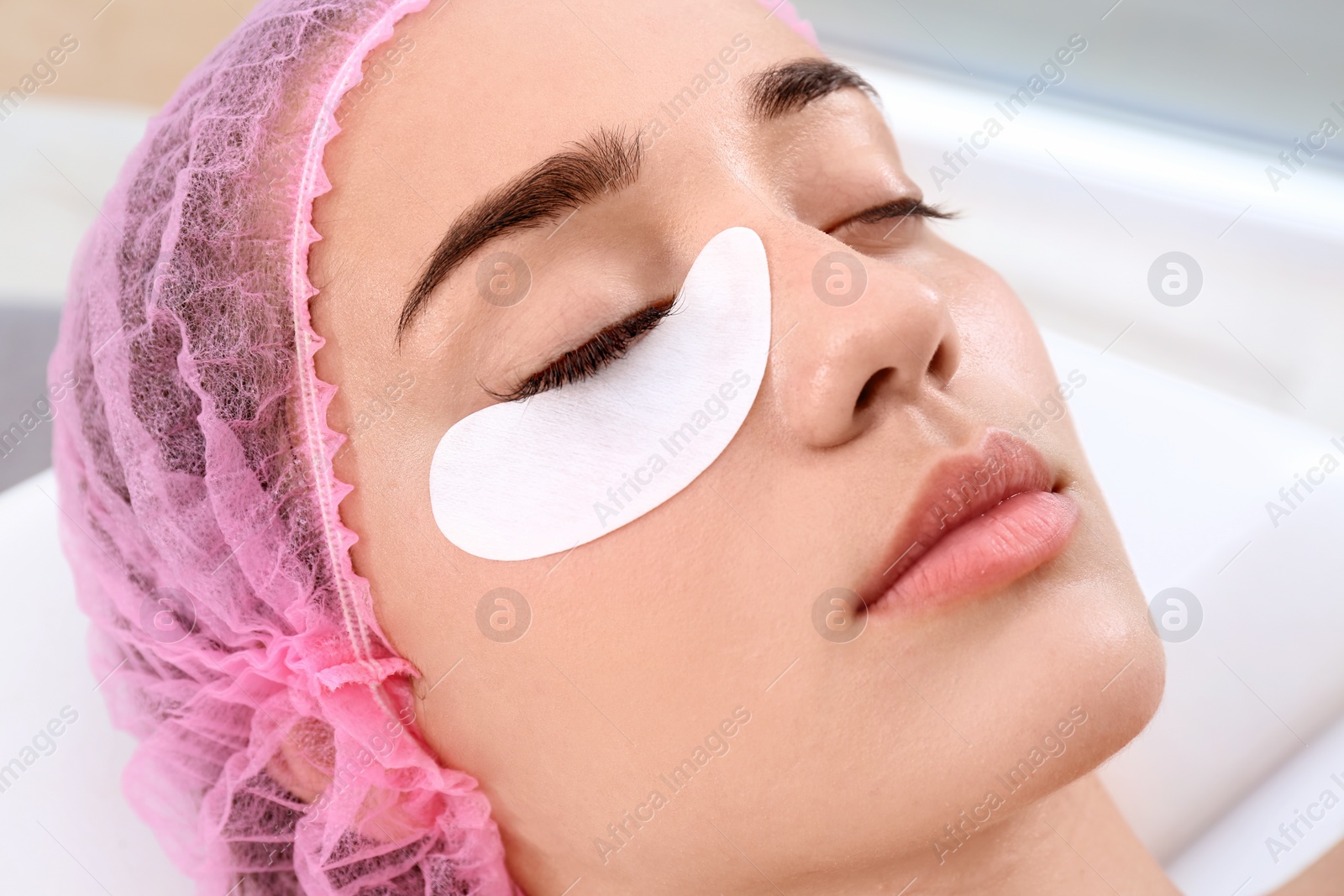 Photo of Young woman undergoing eyelash extensions procedure, closeup