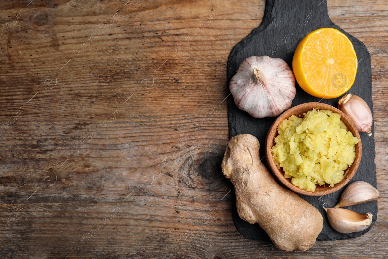 Photo of Fresh garlic and other natural cold remedies on wooden table, top view. Space for text