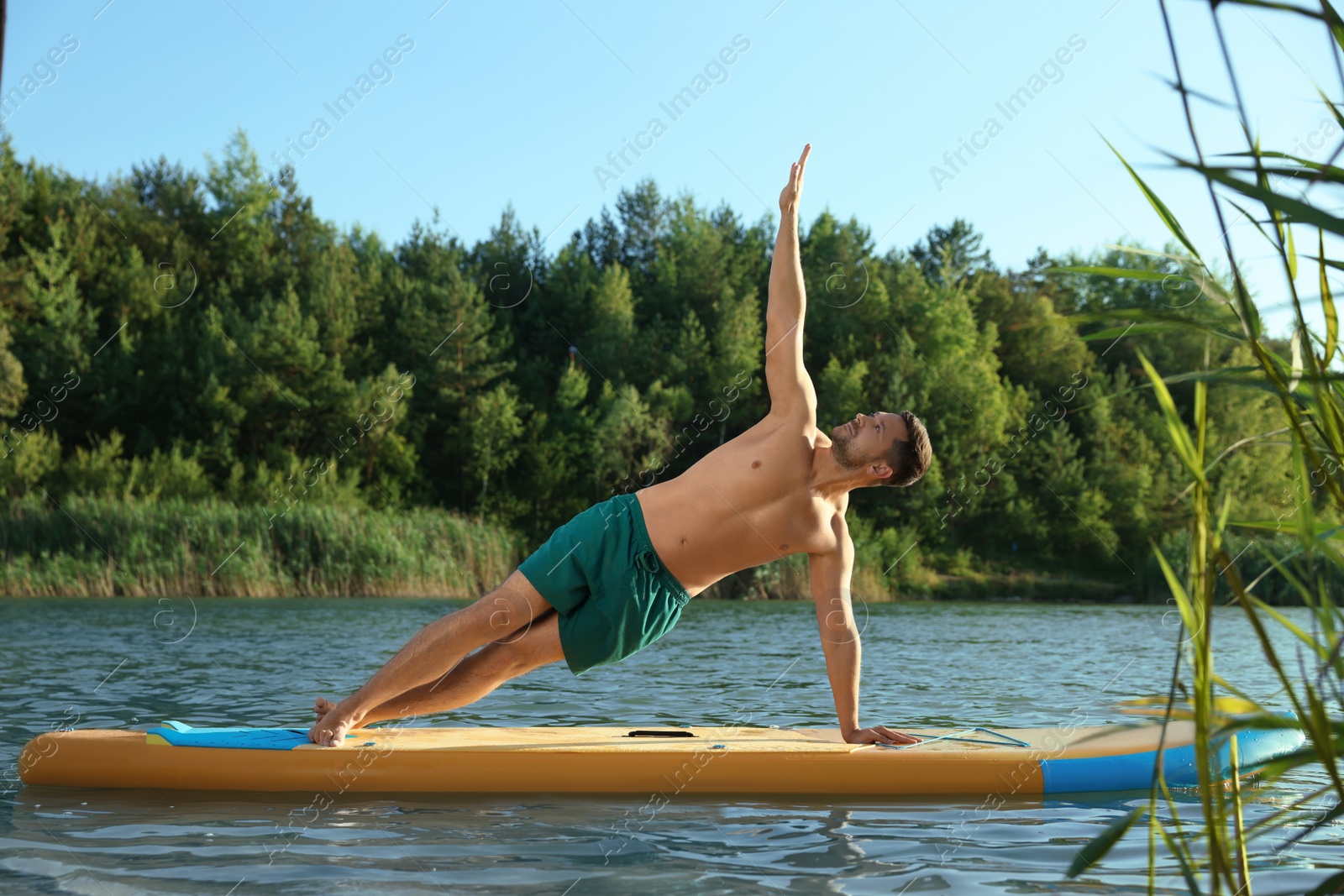 Photo of Man practicing yoga on color SUP board on river