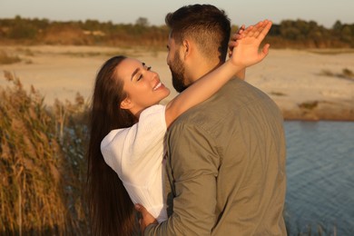 Beautiful couple dancing near river at sunset