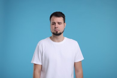 Portrait of sad man on light blue background