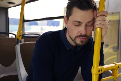 Tired man sleeping while sitting in public transport