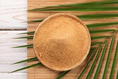 Photo of Coconut sugar, palm leaves and bamboo mat on wooden rustic table, top view