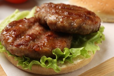 Photo of Delicious fried patties, lettuce and bun on board, closeup. Making hamburger