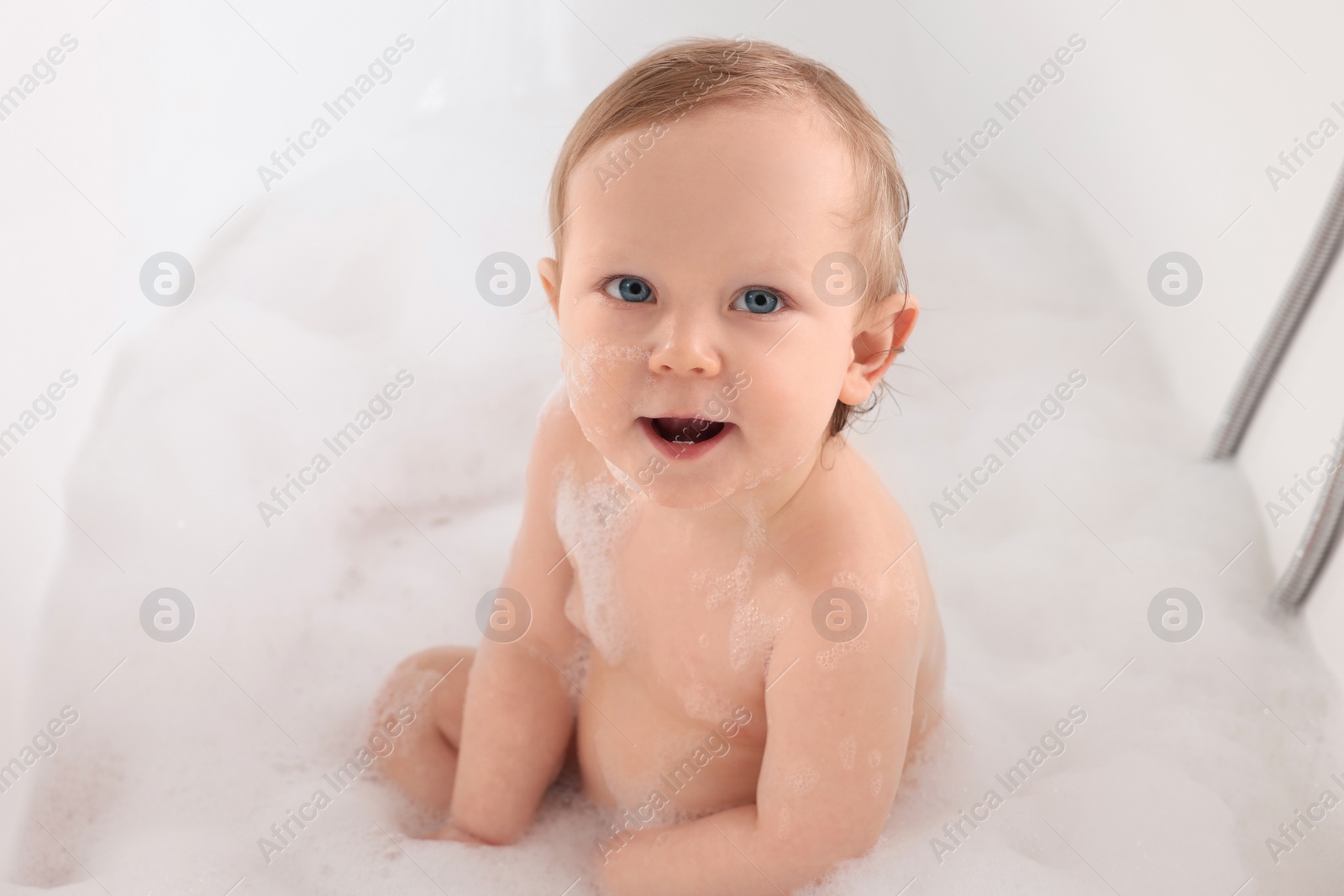 Photo of Cute little baby bathing in tub at home