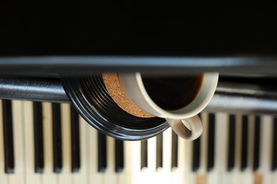 Photo of Cup of delicious coffee on grand piano, closeup