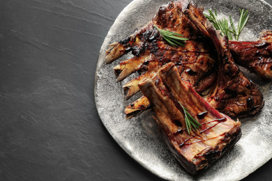 Delicious grilled ribs served on black table, top view. Space for text