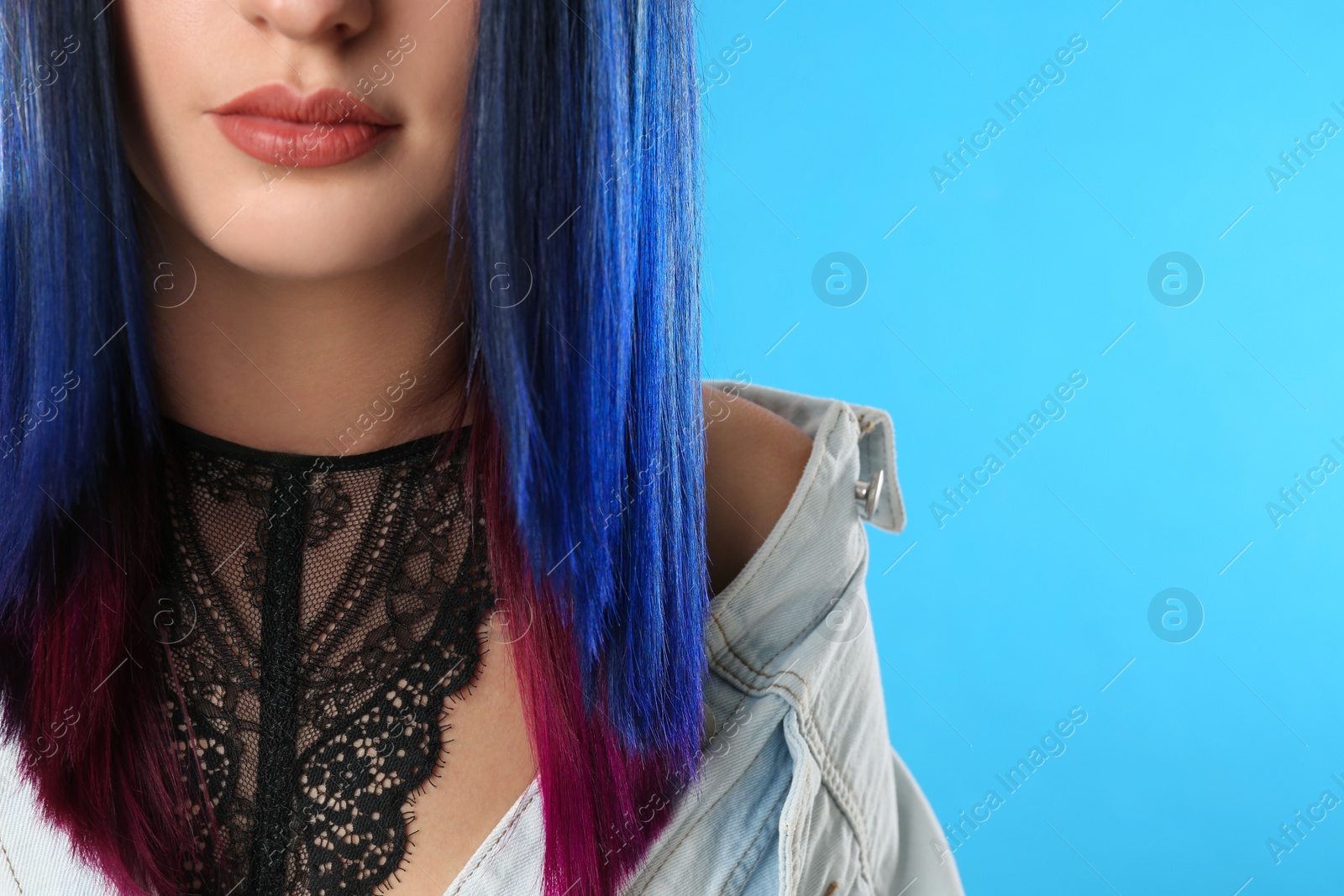 Photo of Young woman with bright dyed hair on light blue background, closeup. Space for text