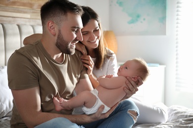 Photo of Happy couple with their newborn baby at home