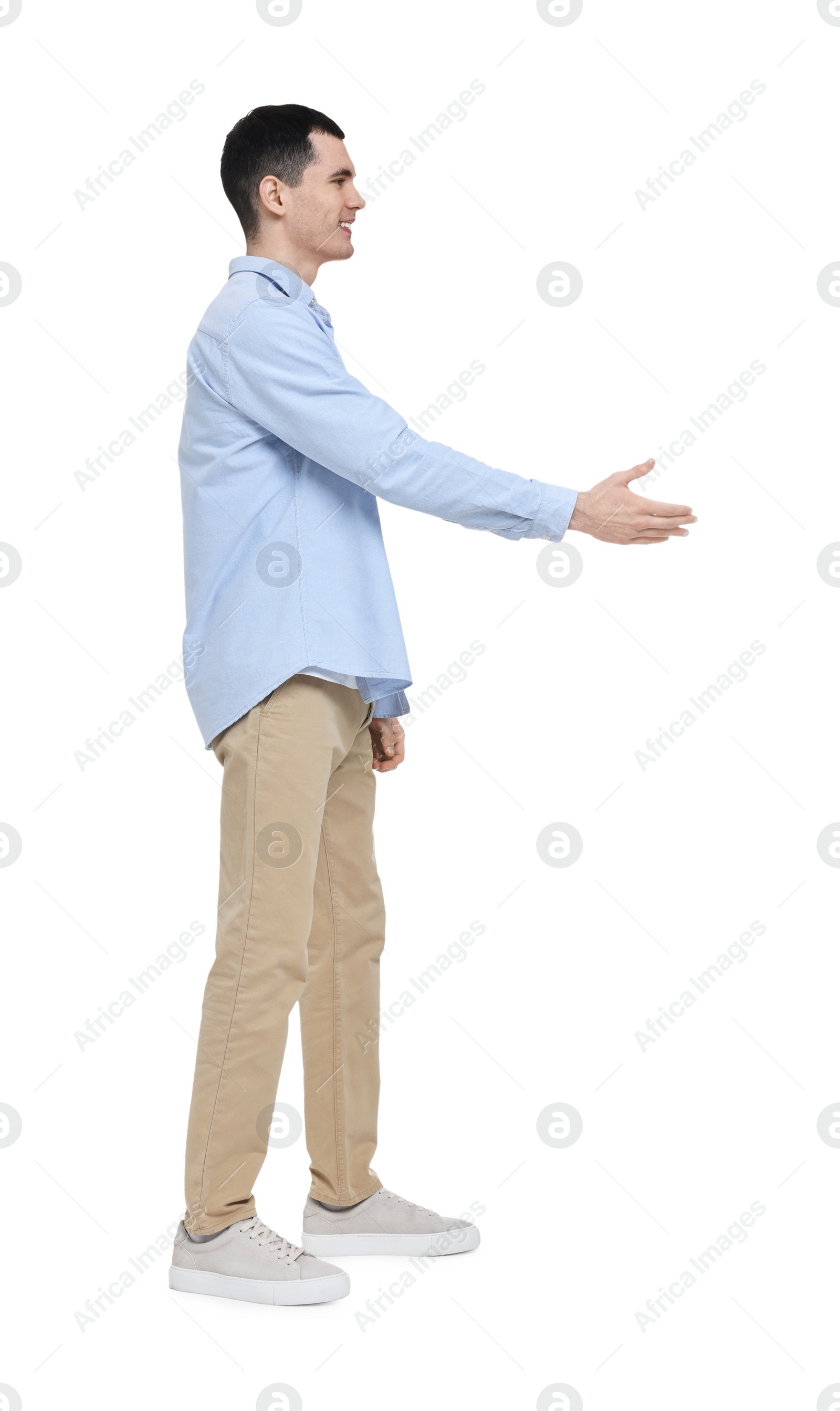 Photo of Young man in light blue shirt and beige pants on white background