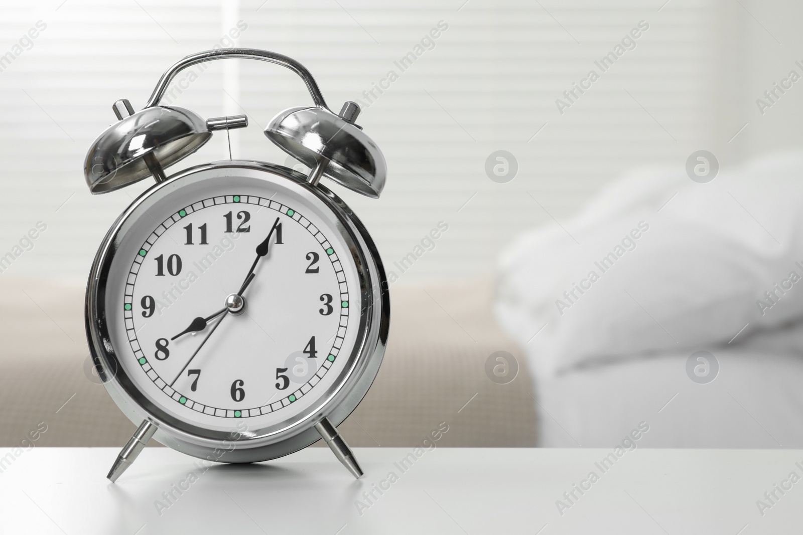 Photo of Silver alarm clock on white wooden table in bedroom, space for text