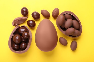 Photo of Delicious chocolate eggs and sweets on yellow background, flat lay