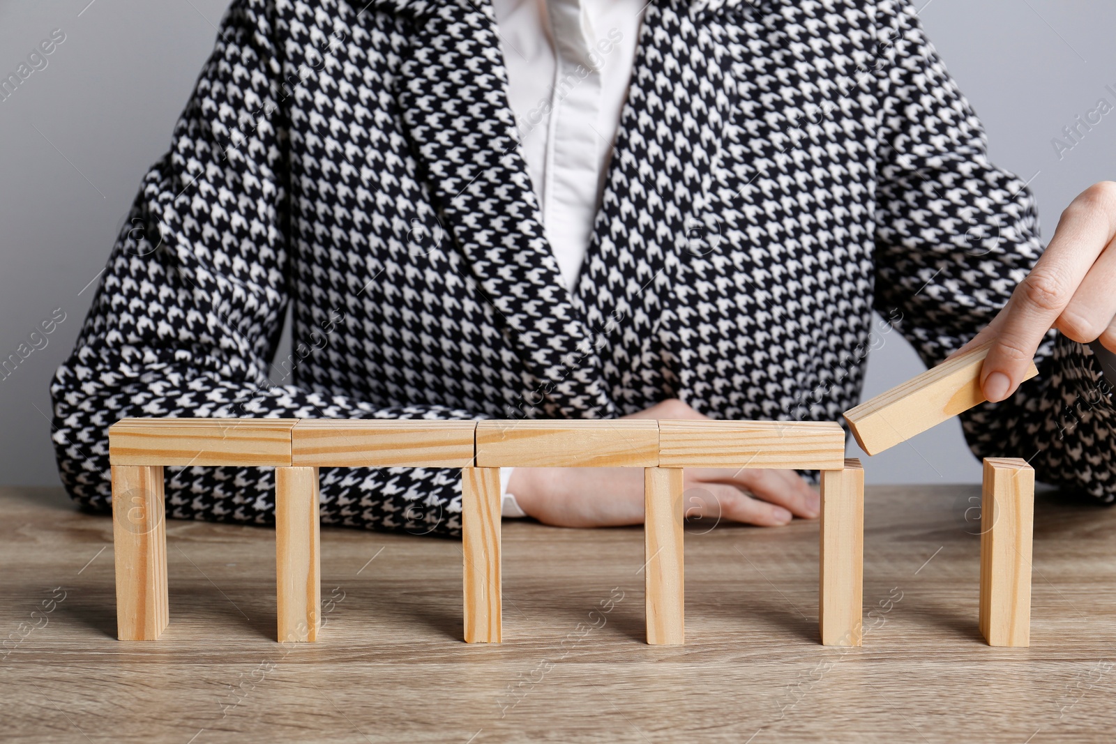 Photo of Businesswoman building bridge with wooden blocks at table, closeup. Connection, relationships and deal concept