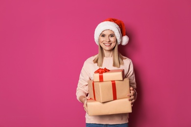 Young woman with Christmas gifts on color background