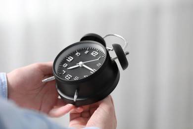 Photo of Man with alarm clock indoors, closeup. Space for text
