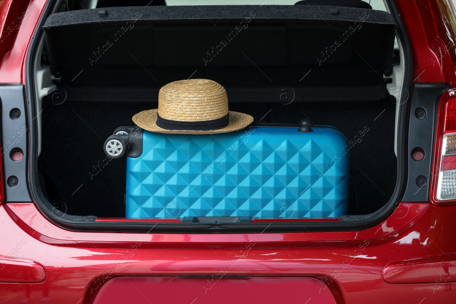 Photo of Suitcase and hat in car trunk outdoors, closeup