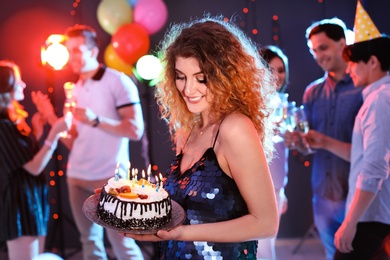 Young woman with birthday cake at party in nightclub