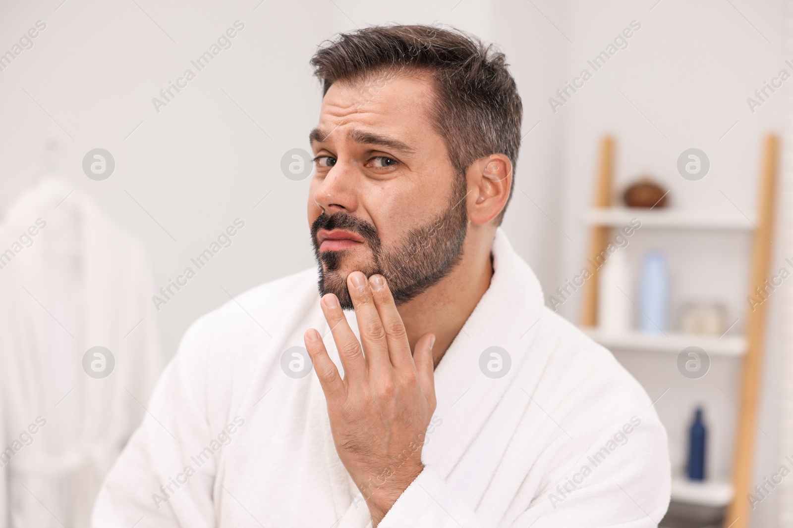 Photo of Skin problem. Confused man touching his face at home