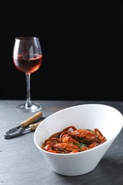Photo of Delicious boiled crabs, glass of wine and cracker on grey table, space for text