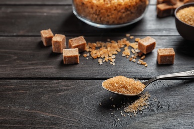 Spoon with brown sugar on wooden table