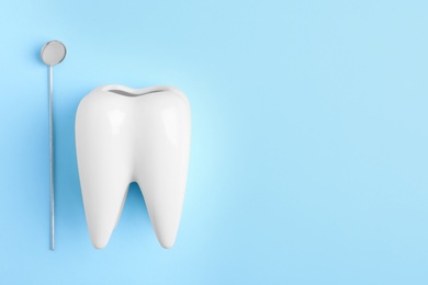 Photo of Dentist mirror and tooth shaped holder on color background, top view with space for text