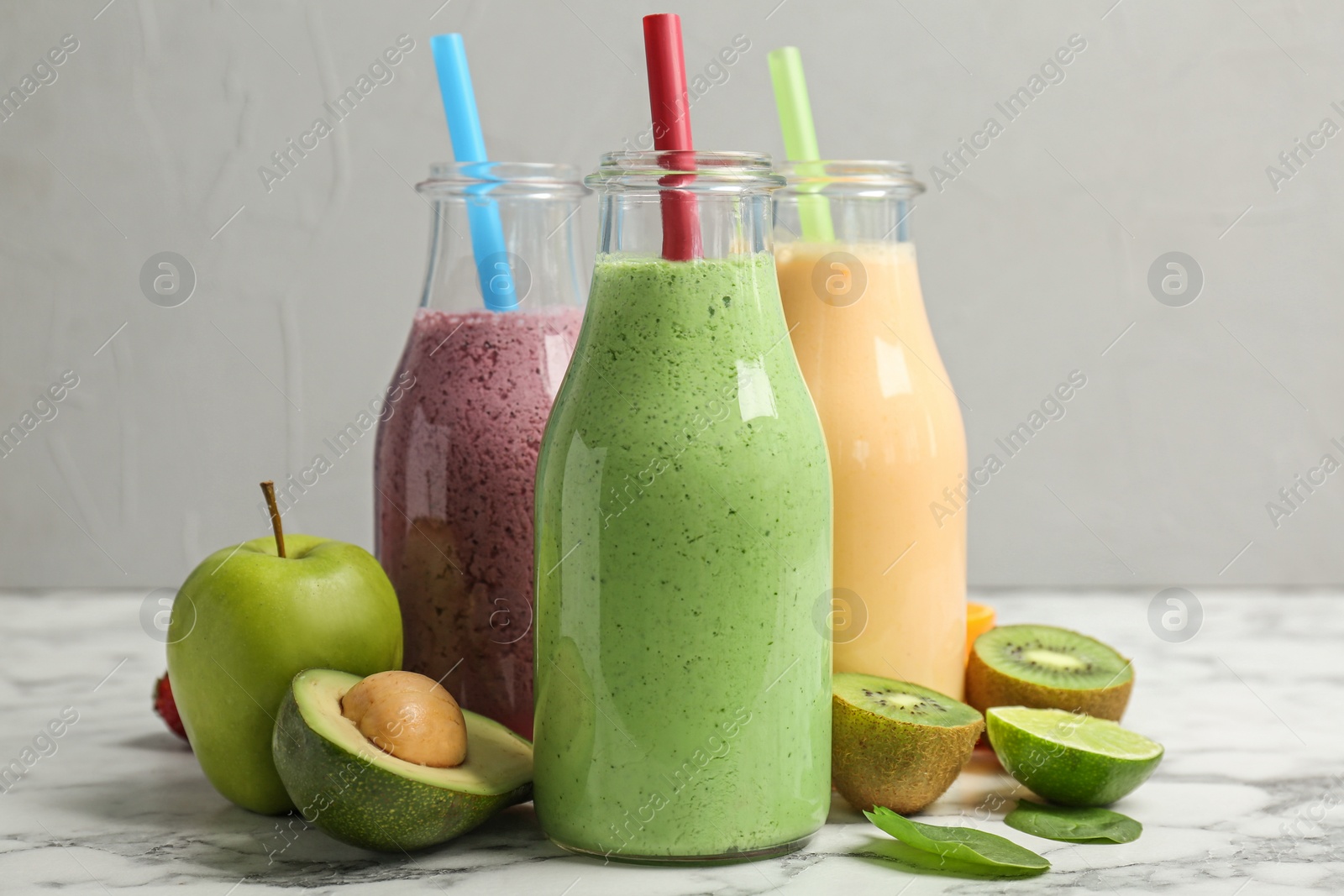 Photo of Bottles with healthy detox smoothies and ingredients on table