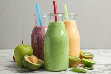 Bottles with healthy detox smoothies and ingredients on table