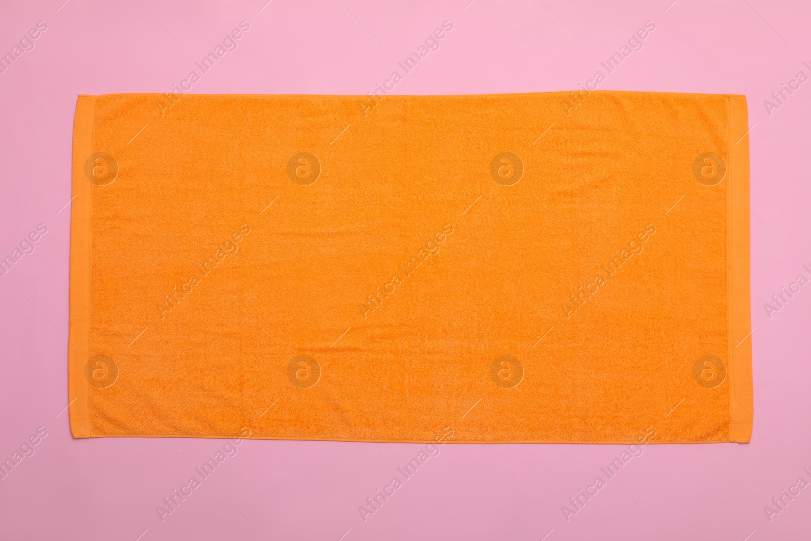 Photo of Orange beach towel on pink background, top view
