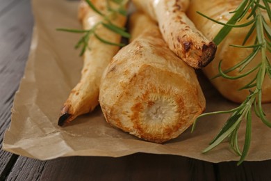Tasty baked parsnips with rosemary on wooden table, closeup
