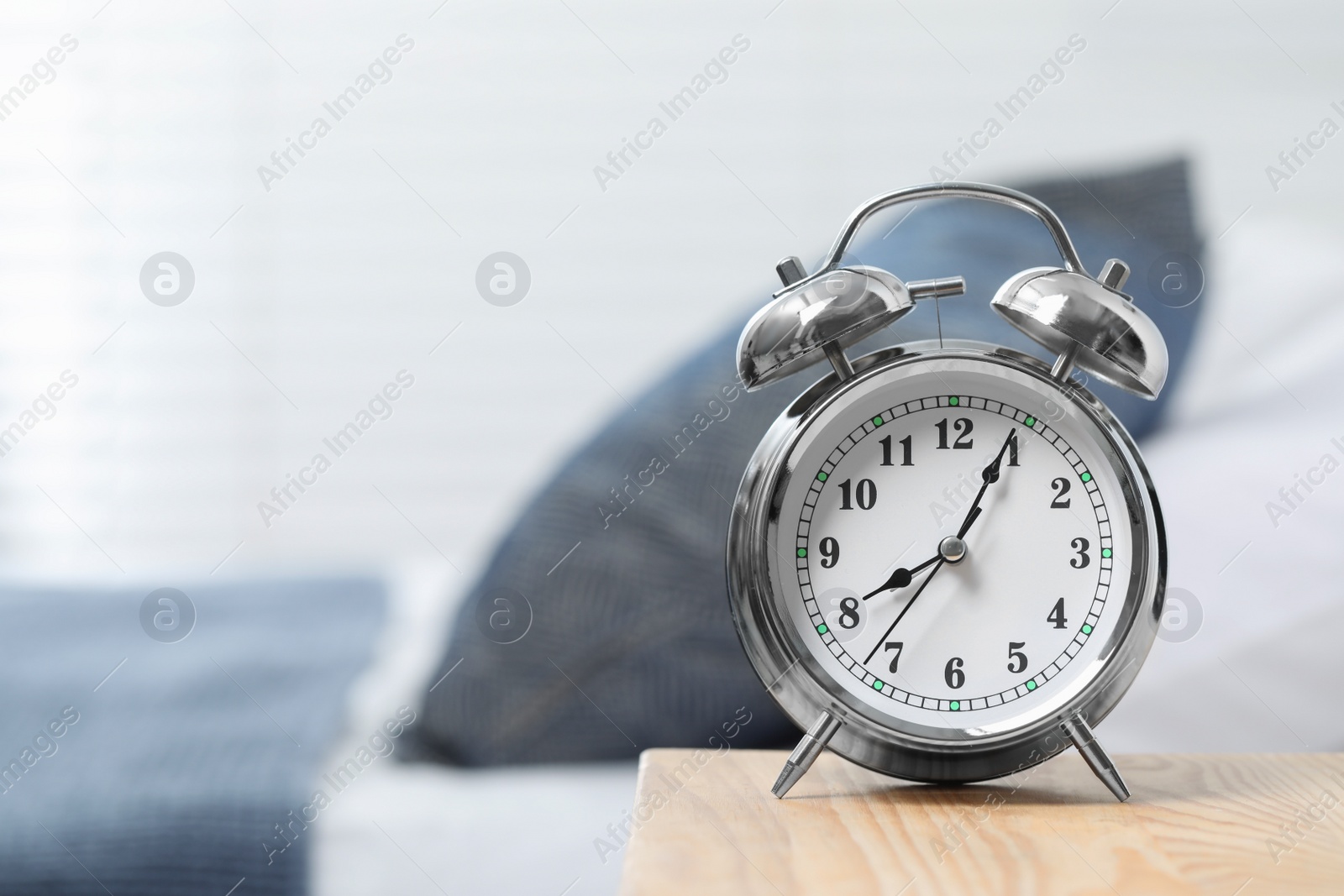 Photo of Silver alarm clock on wooden nightstand in bedroom, space for text