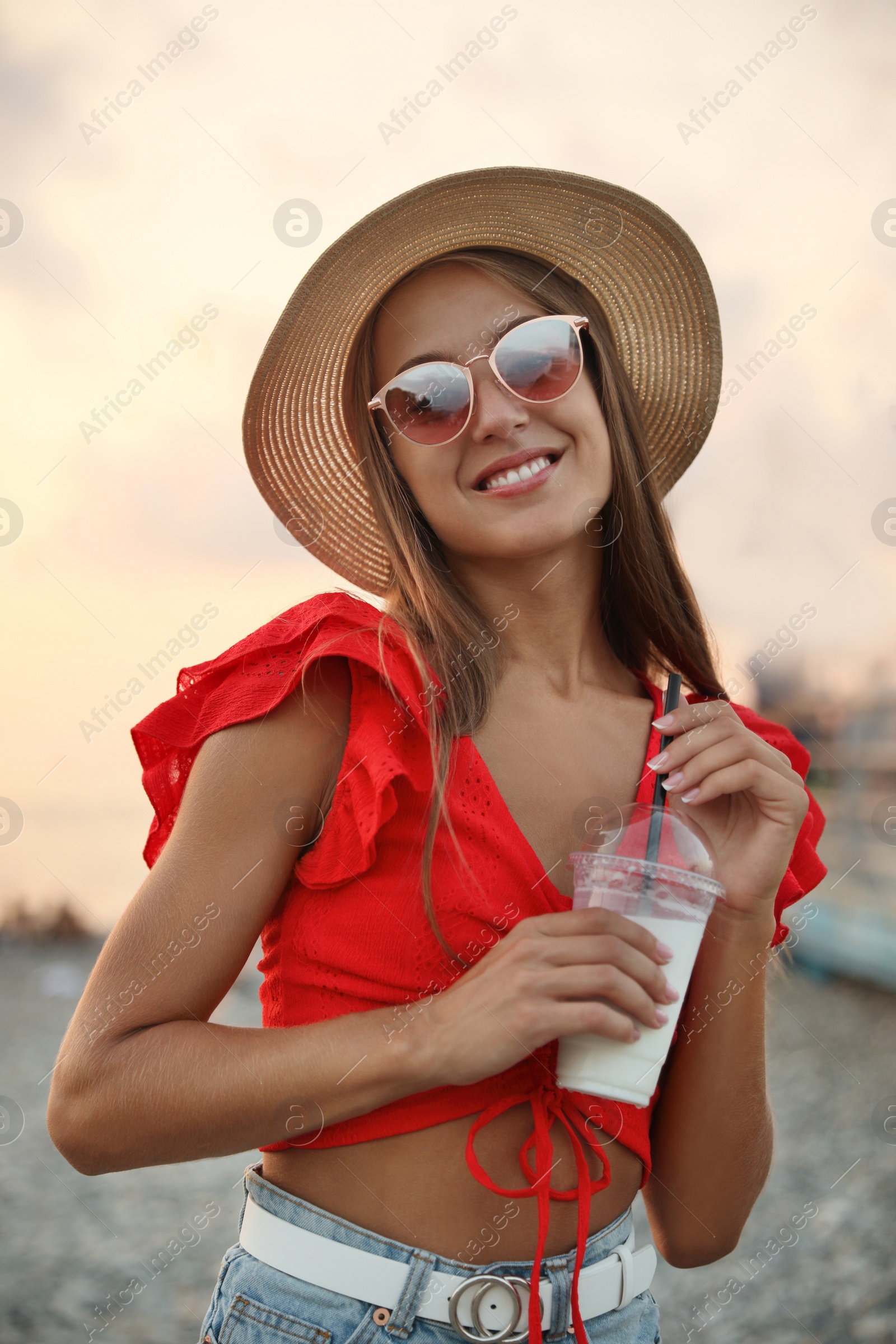 Photo of Beautiful young woman with tasty milk shake on beach