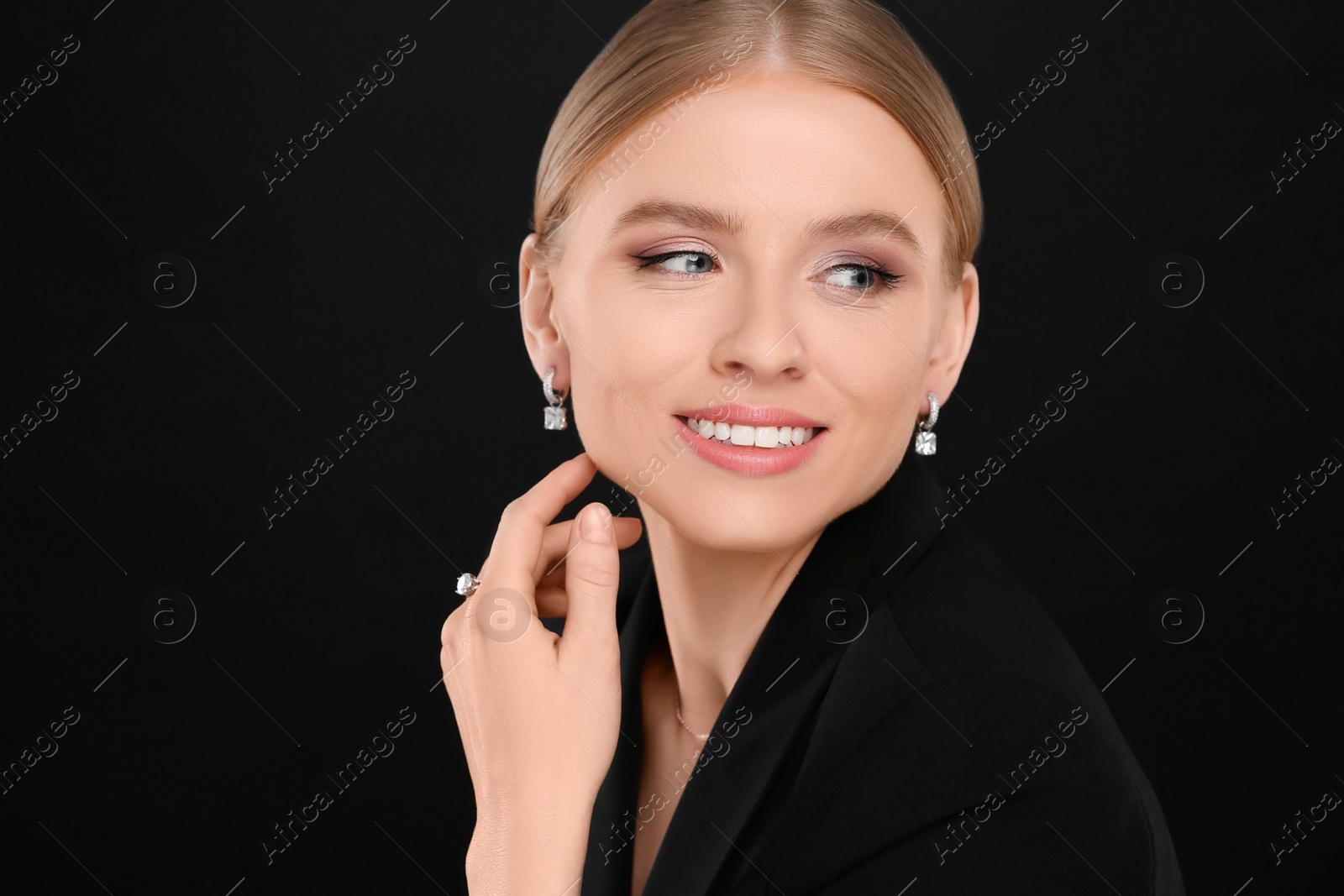 Photo of Beautiful young woman with elegant jewelry on black background