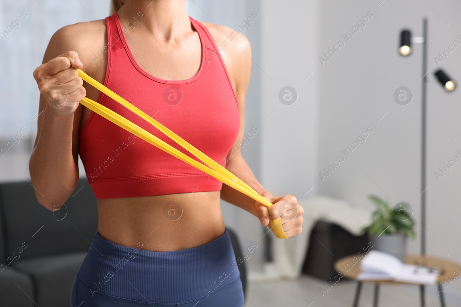 Photo of Woman doing exercise with fitness elastic band at home, closeup