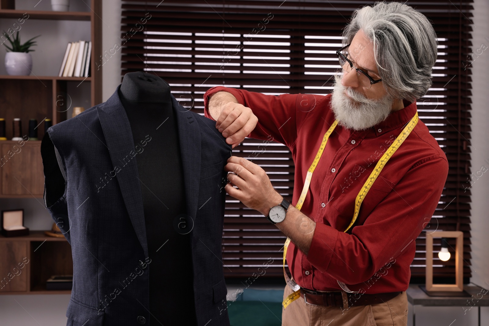 Photo of Professional tailor working with mannequin in atelier