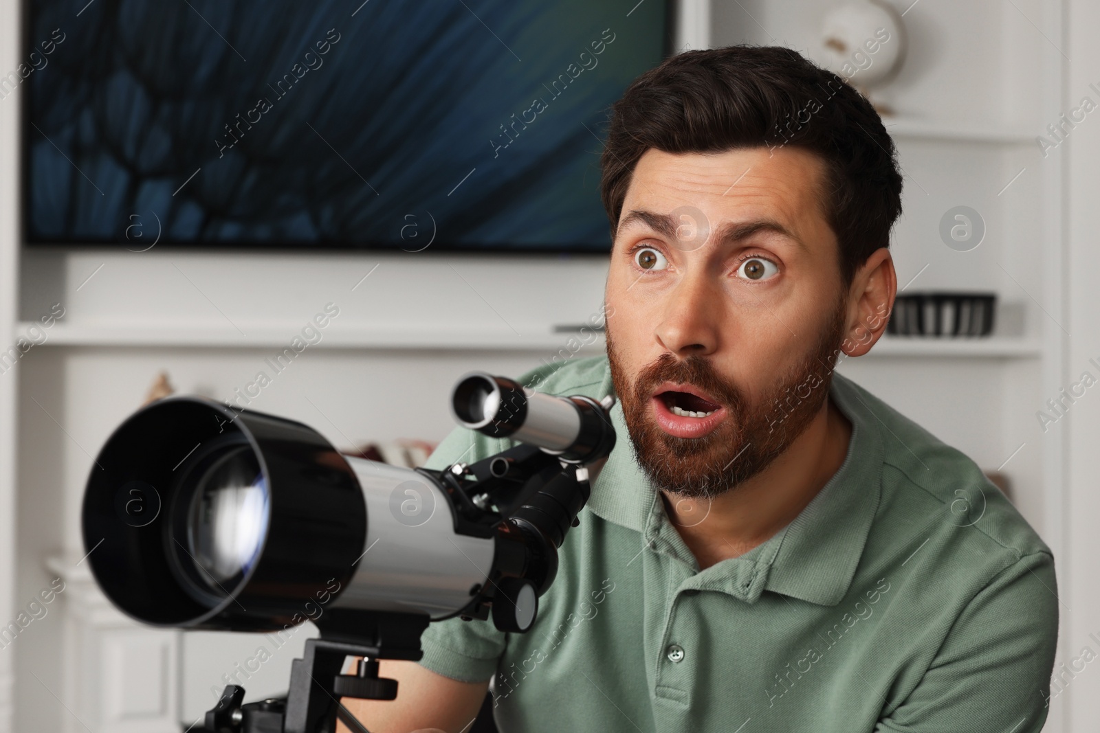 Photo of Emotional man using telescope to look at stars in room