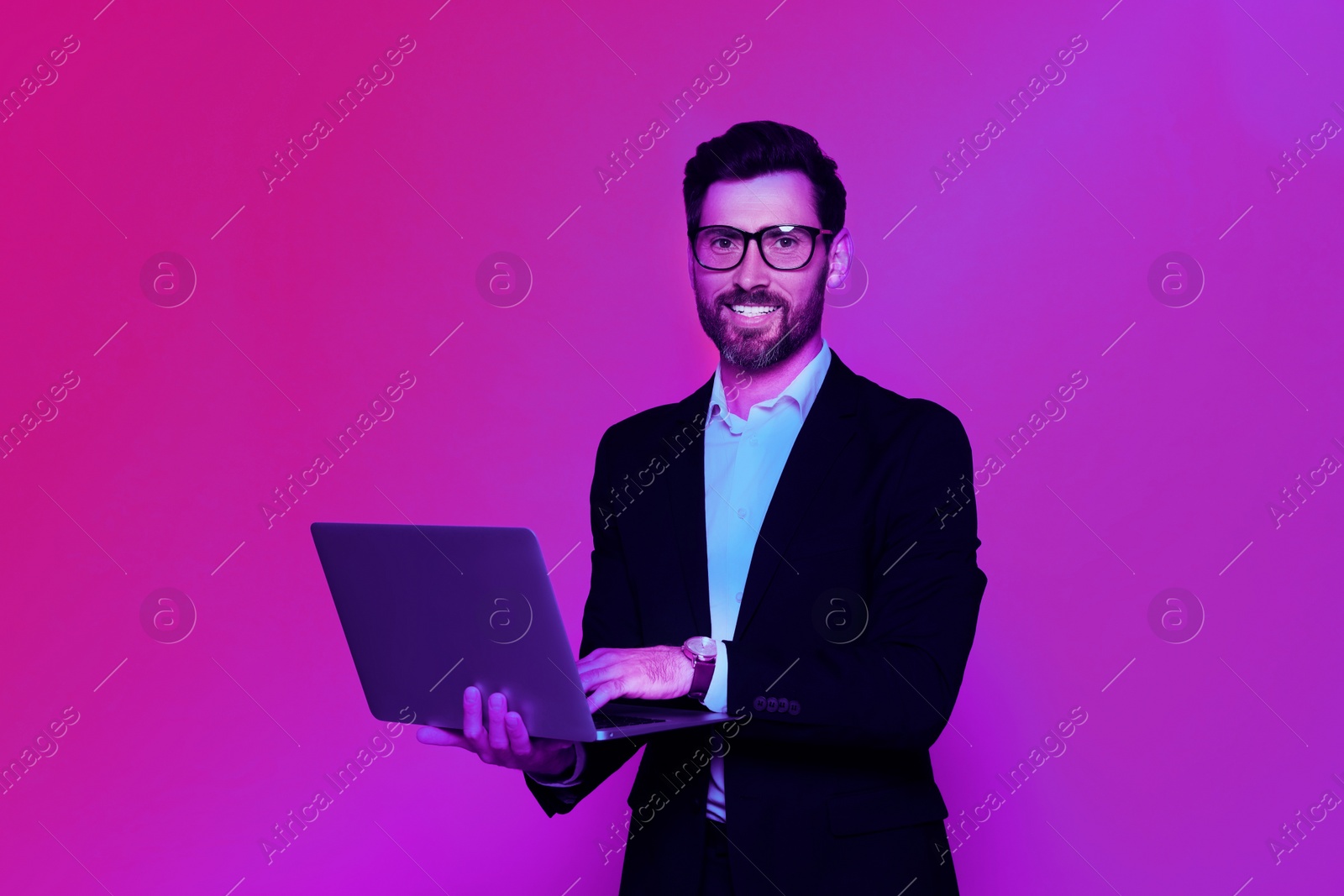 Image of Handsome man with laptop in neon lights