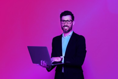 Image of Handsome man with laptop in neon lights