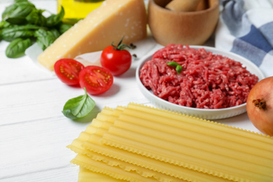 Fresh ingredients for lasagna on white wooden table