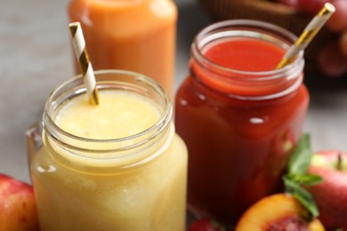 Photo of Mason jars of delicious juices with straws, closeup