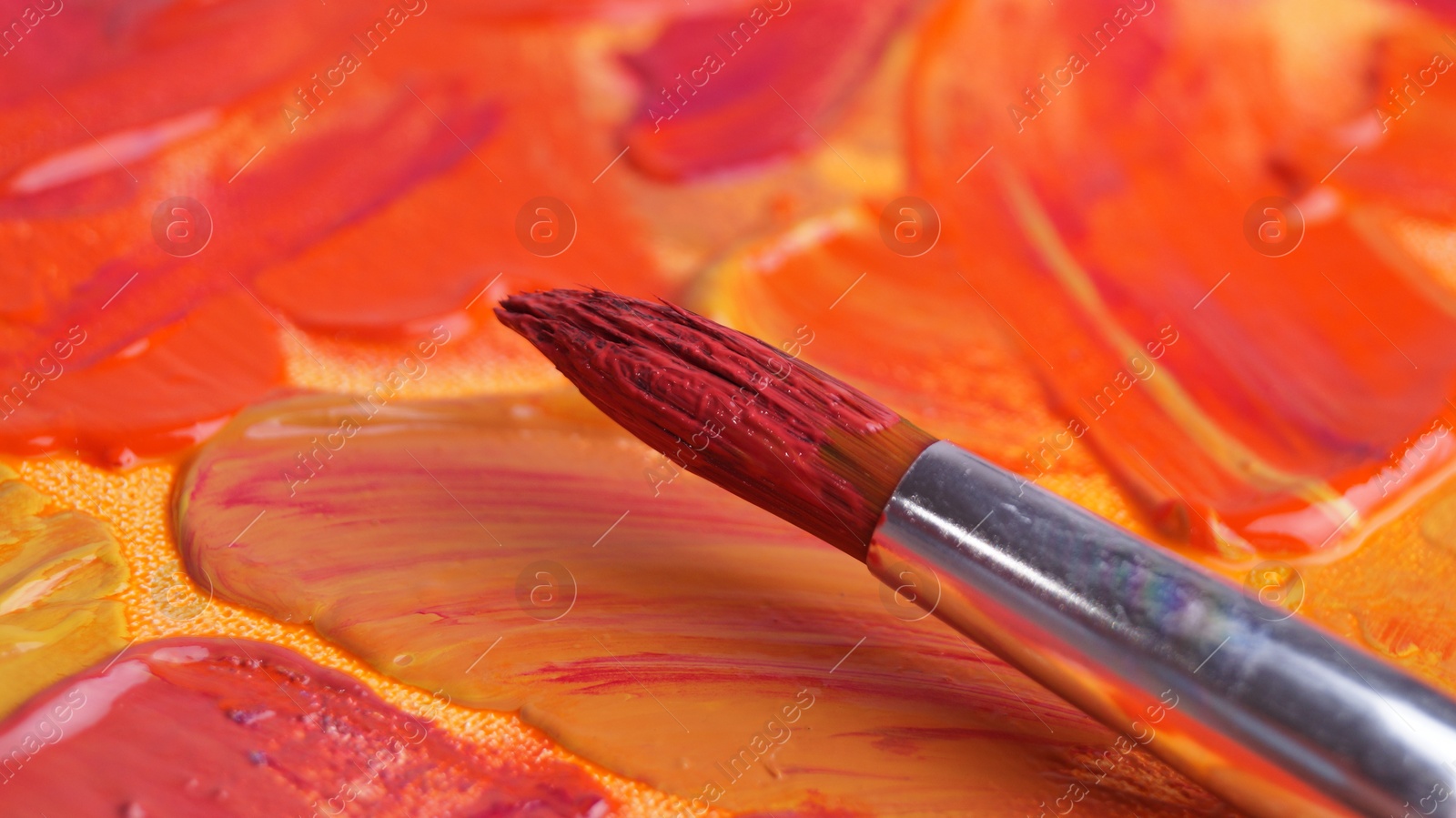 Photo of Brush on artist's palette with mixed paints, closeup