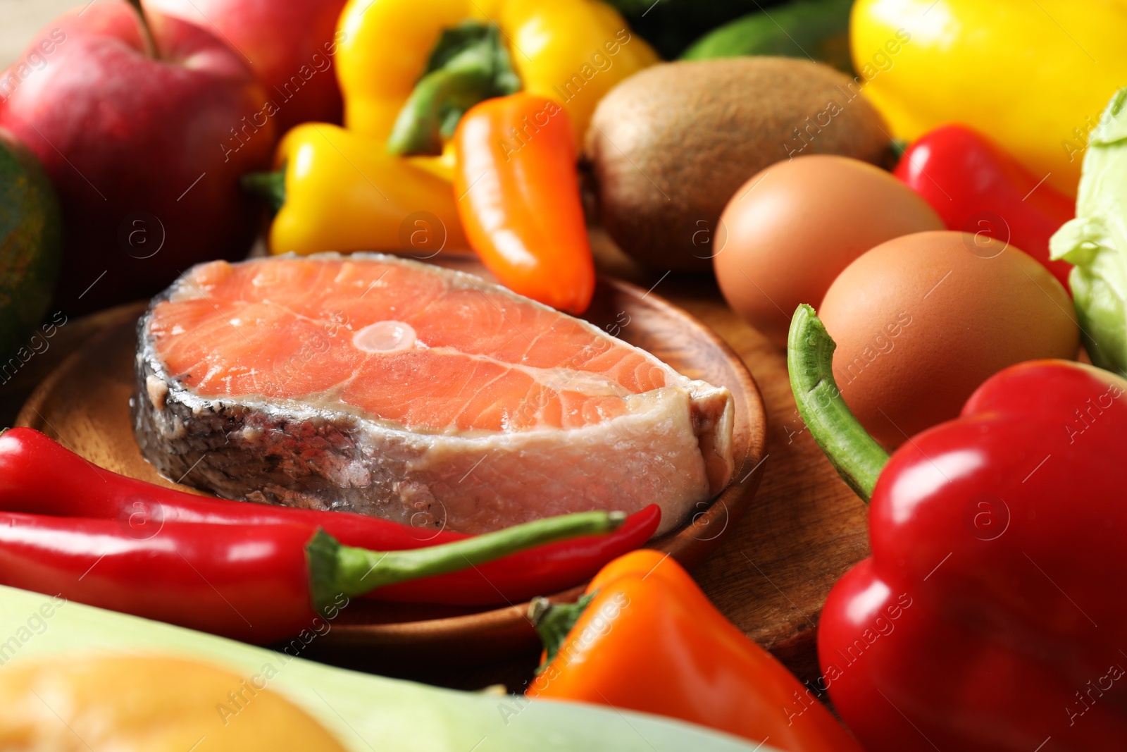 Photo of Healthy meal. Different vegetables and raw salmon on wooden table, closeup