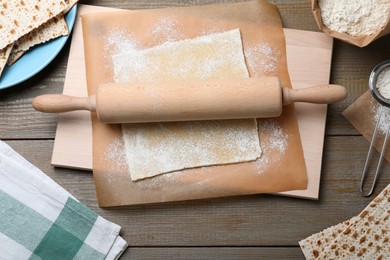Photo of Matzos and raw dough on wooden table, flat lay
