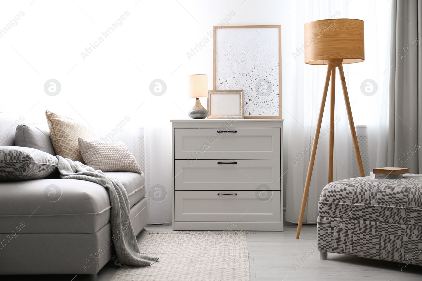 Photo of Modern stylish chest of drawers near window in living room. Interior design