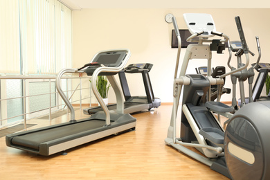 Photo of Elliptical trainers and treadmills in gym. Modern sport equipment