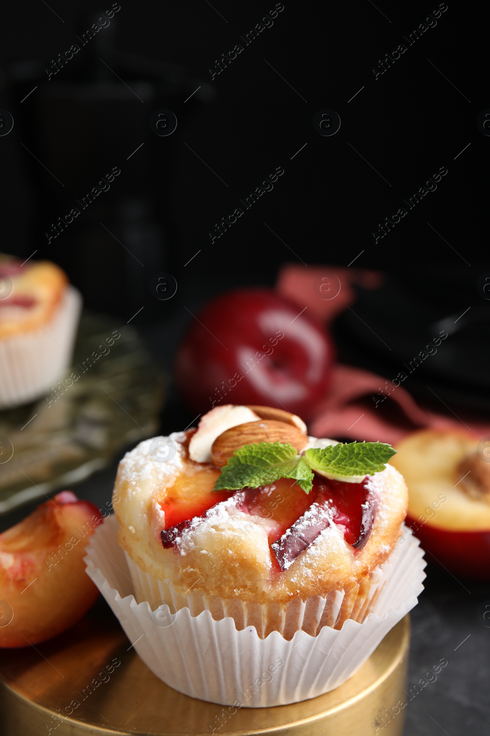 Photo of Delicious cupcakes with plums on black table, closeup