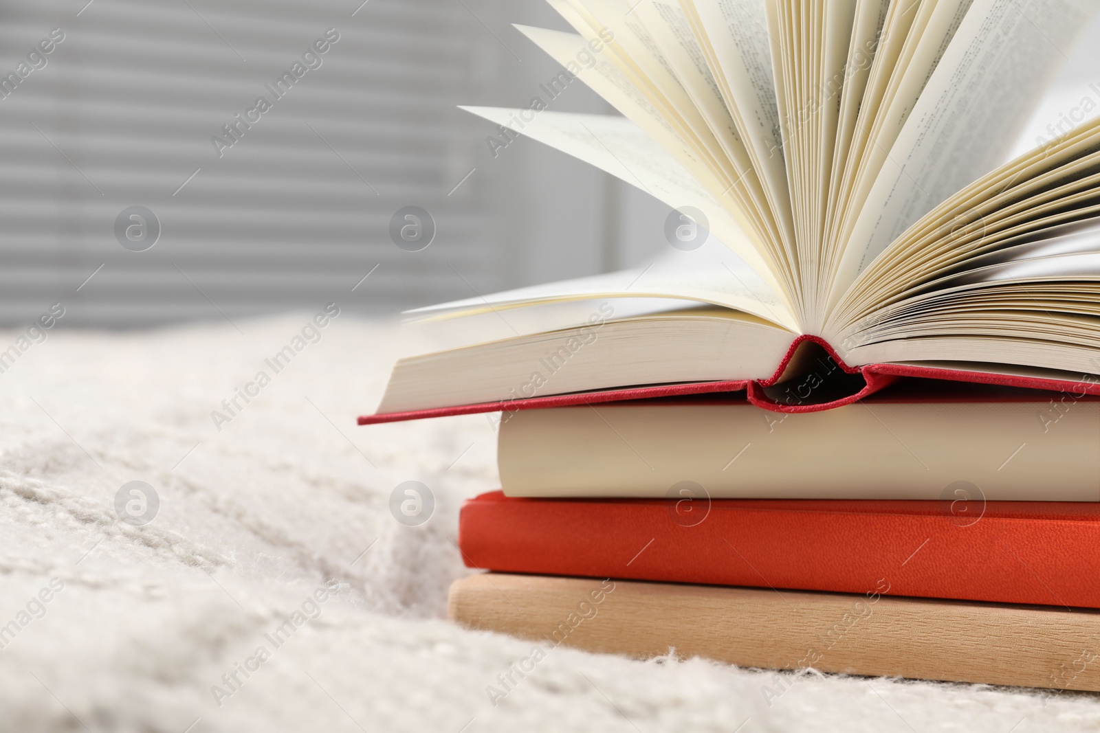 Photo of Books on white soft blanket in bedroom, closeup. Space for text