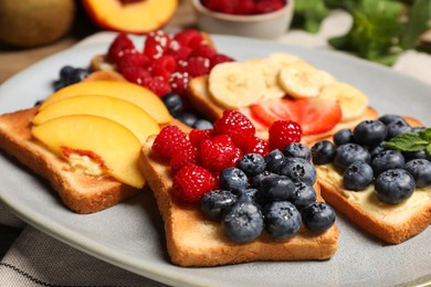 Tasty toasts with different spreads and fruits on plate, closeup