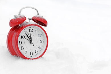 Photo of Red alarm clock on white snow outdoors. Space for text